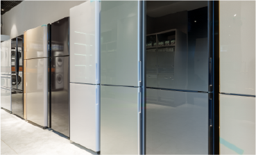 A lineup of modern refrigerators in various finishes, including white, beige, and glossy grey, standing side-by-side in a showroom