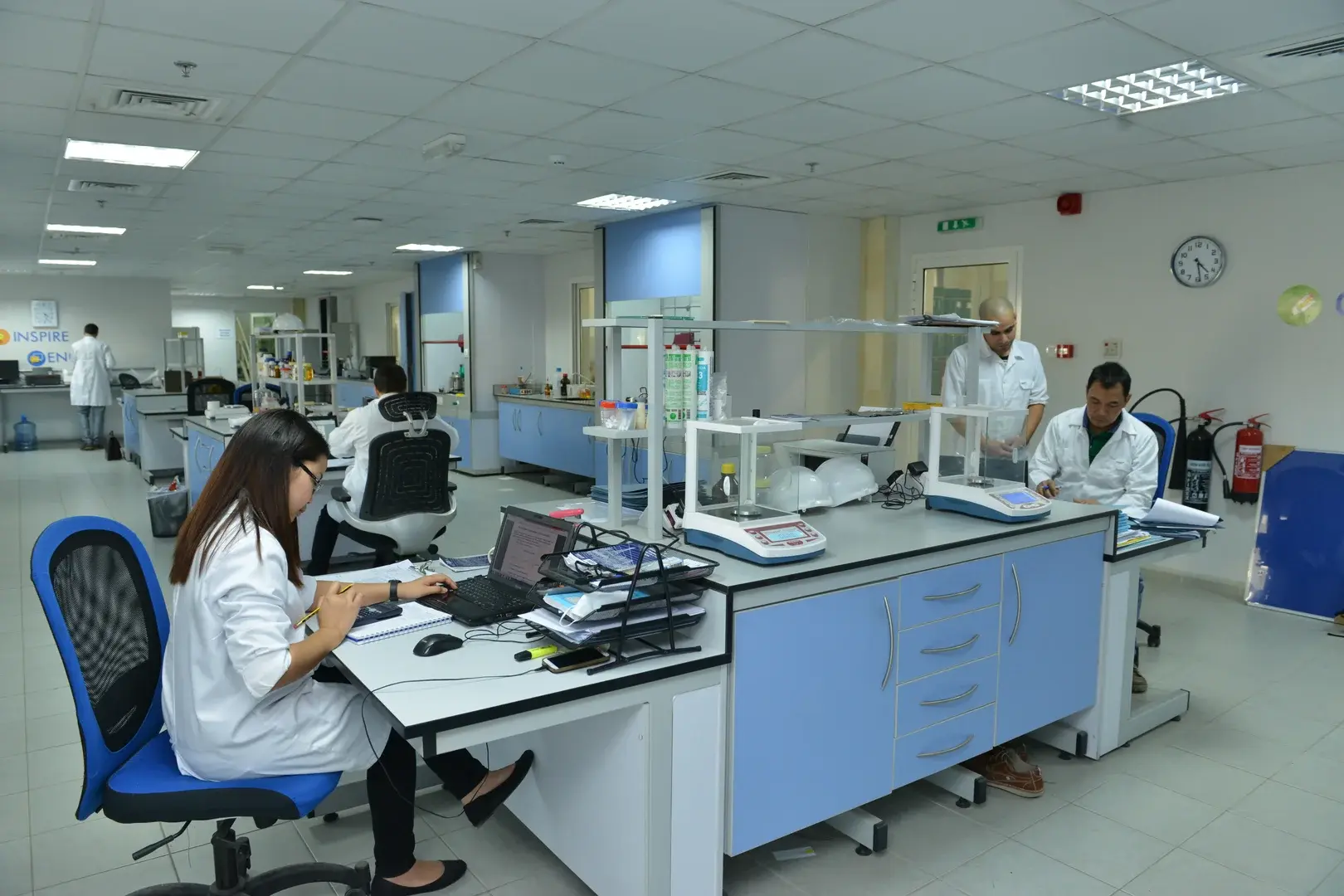 Scientists working in modern laboratory with blue cabinets computers and research equipment